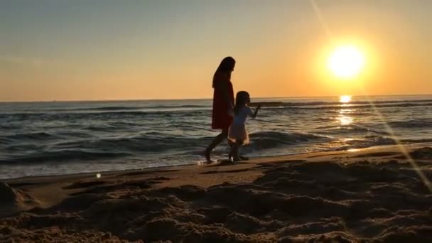 Kleines Mädchen und junge Frau laufen am Strand entlang. — Stockvideo