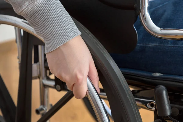 Detalle de la mujer discapacitada sosteniendo una mano sobre el volante de una silla de ruedas — Foto de Stock
