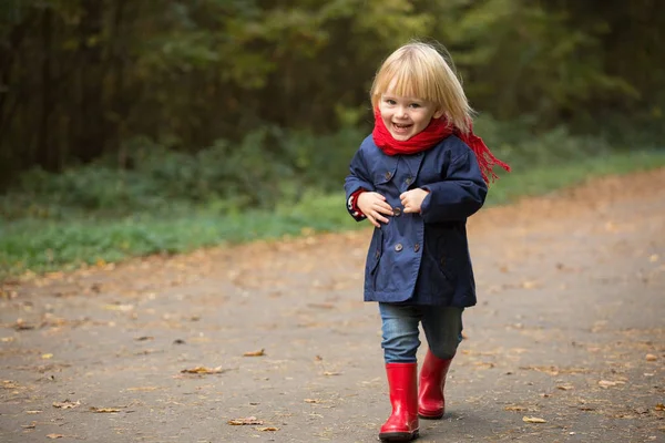 Feliz Outono. Menina ri e corre em galochas através do th — Fotografia de Stock