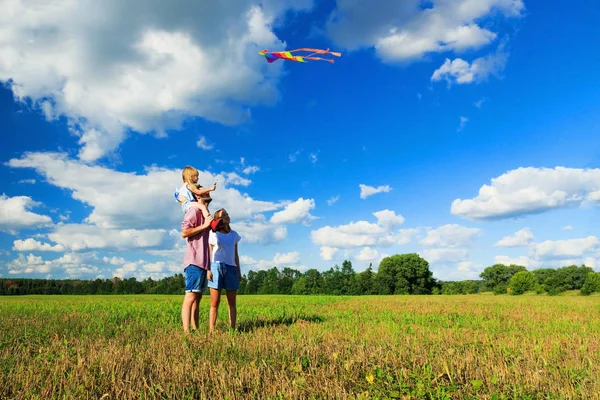 Madre, padre e hija están volando una cometa en el campo. Fron —  Fotos de Stock