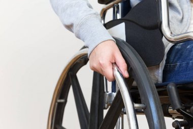Tekerlekli sandalyede el ele tutuşan engelli kadın detayları.