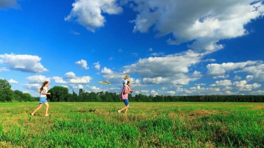 Anne, baba ve kızı tarlada uçurtma uçuruyorlar..