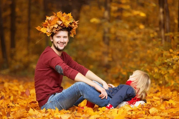 Father and daughter. They sit in the park and play with the leav — Stock Photo, Image