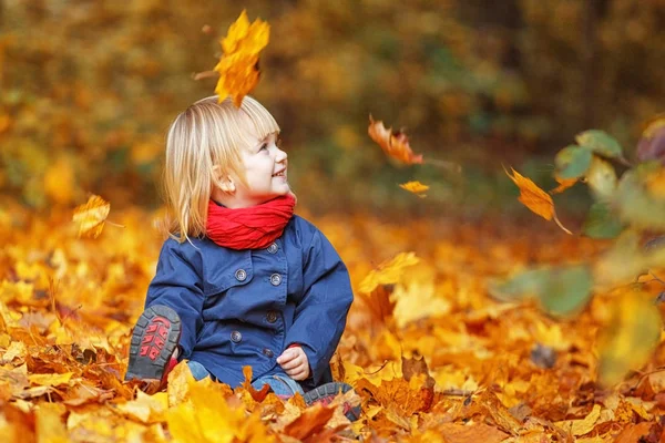Feliz Outono! Pequena menina doce brincando com folhas em um outono — Fotografia de Stock