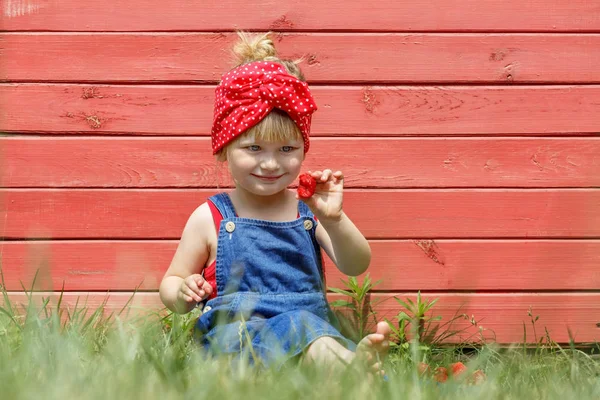 Liten flicka äter söta jordgubbar på en solig dag. — Stockfoto