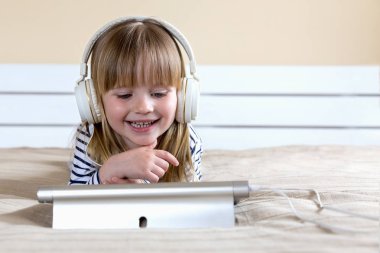 Llittle kız beyaz kulaklıkyabancı dil öğreniyor.