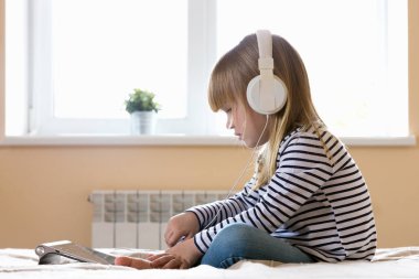 Pencerenin yanında tablet kullanan küçük kız. 