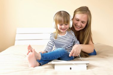 Anne ve kızı yatakta birlikte tablet kullanarak. 