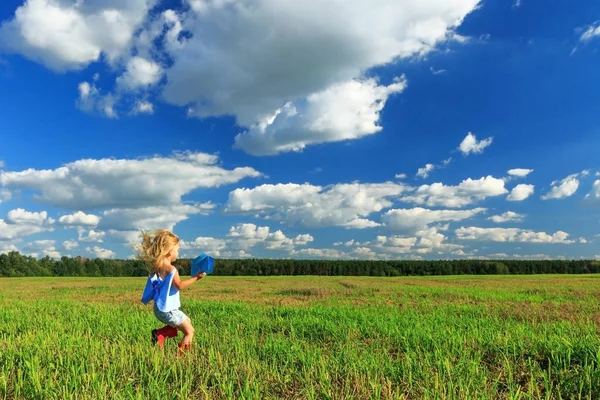 Маленька дівчинка тримає паперовий літак в руці і бігає в літаку — стокове фото