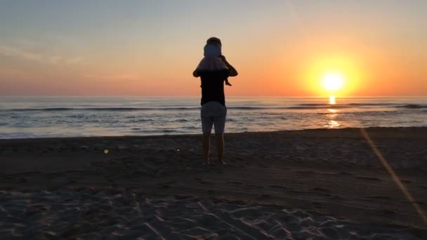 Πατέρας και κόρη που στέκεται στην παραλία το ηλιοβασίλεμα. — Αρχείο Βίντεο