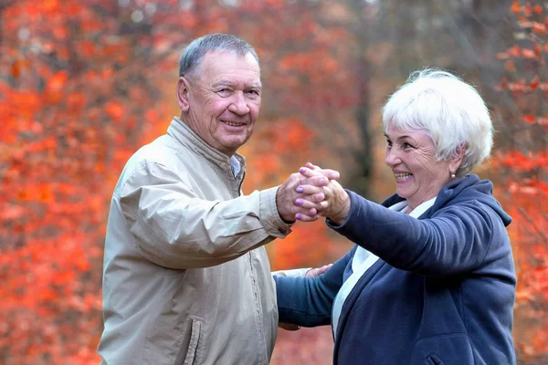 Happy elderly couple dancing in an autumn walk