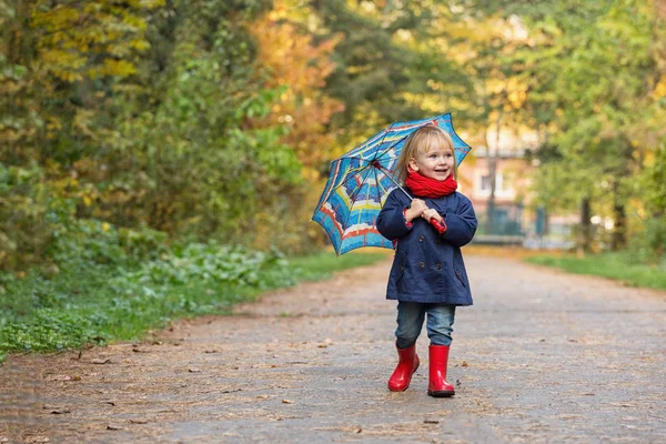 Lastik çizme ve yağmurluk giymiş küçük bir kız, — Stok fotoğraf