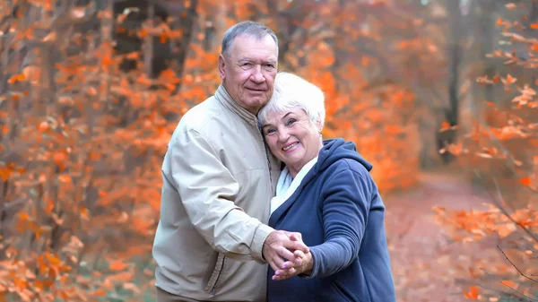 Feliz casal sênior abraços e olhando para câmera — Fotografia de Stock