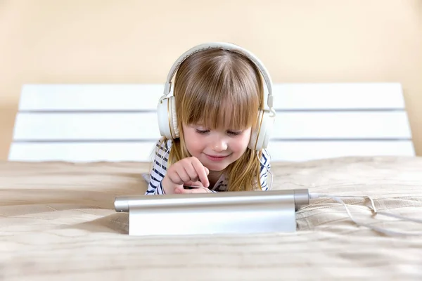 Niña acostada en la cama y usando tableta . —  Fotos de Stock