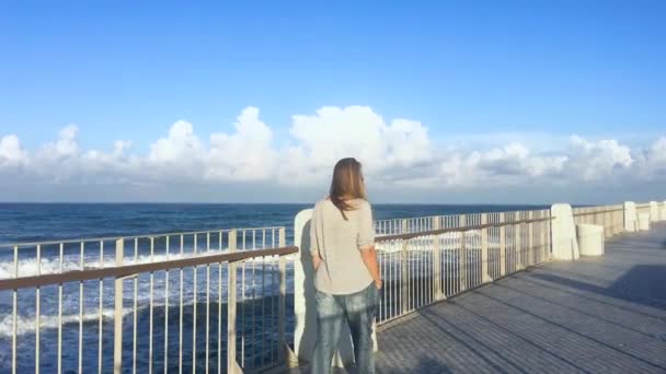 Slow Motion gelukkige vrouw wandelen op de zee Pier bij zonsondergang. — Stockvideo