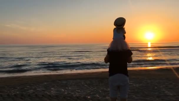 Πατέρας και κόρη που περπατούν στη θάλασσα το ηλιοβασίλεμα. — Αρχείο Βίντεο