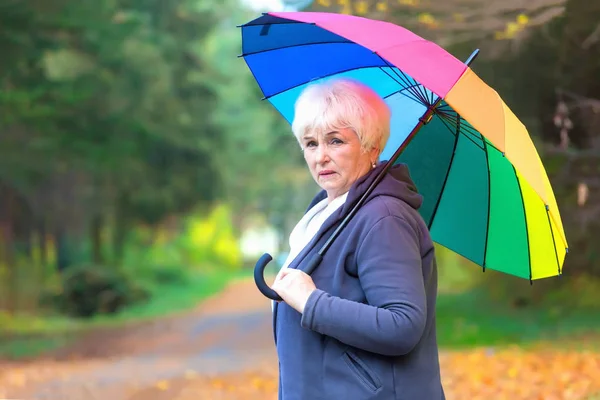 Занепокоєна старша жінка з барвистою парасолькою — стокове фото