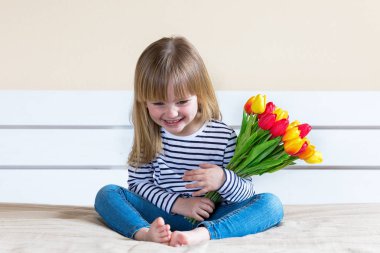 Küçük kız oturuyor ve gülümsüyor