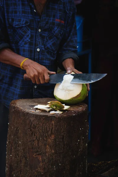 Man cuts young green coconut with a sharp chopper — Stock Photo, Image