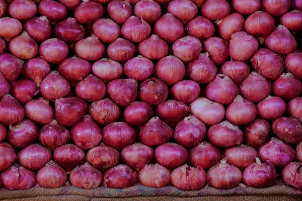 Свежий красный лук, лежащий в ряд на овощном рынке — стоковое фото