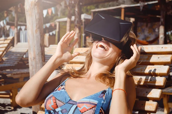 A young beautiful skinny woman having fun with VR glasses on the summer beach