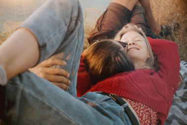 Sarışın bir kadın ve bir battaniye var, açık havada sunrise sarılma ve tüyler ürpertici kazak uzun saçlı esmer adam bir hipster çift.