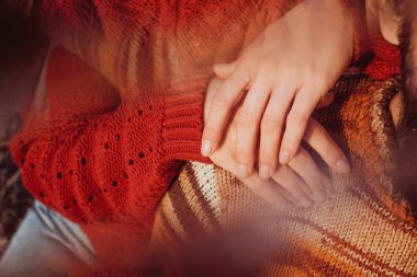 Kadın kırmızı kazaklı erkeğini omzuna elele.