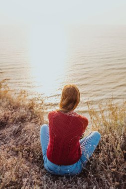 Güzel bir kız redsweater ve ukulele battaniye deniz kenarında oynamaya güneş gözlüğü.
