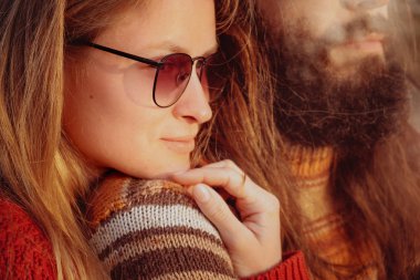 Hipster kaç sarılma ve having fun açık havada gündoğumu içinde güneş gözlüğü içinde gülümseyen. Sakallı adam ve sarışın kadın.