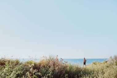 Kazak açık havada güneşin doğuşunu denize yakın kayalık deniz kenarı yürüyüş uzun bir yetişkin adam