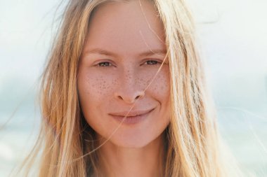 Genç güzel bir zarif ve doğal sarışın kadının mavi elbiseli deniz arka planda ile yakın çekim ortrait