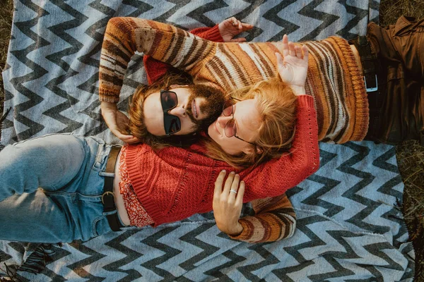 Sarışın bir kadın ve bir battaniye var, açık havada sunrise sarılma ve tüyler ürpertici kazak uzun saçlı esmer adam bir hipster çift.