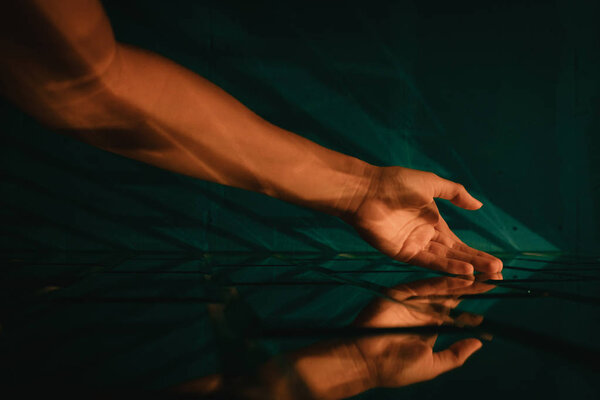 Женская рука касается стилизованной дизайнерской зеленой кирпичной стены
