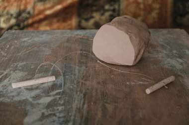 Piece of clay cut with string lying on wooden table prepared for pottery wheel
