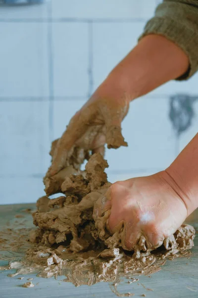 Primer plano manos femeninas mezclando bola de arcilla antes de trabajar en una rueda de cerámica — Foto de Stock