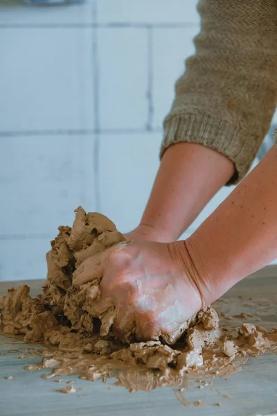 Primer plano manos femeninas mezclando bola de arcilla antes de trabajar en una rueda de cerámica — Foto de Stock