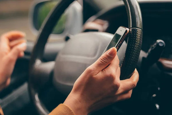 Close up woman driving car and using navigation or gps on mobile smartphone. Blurred car interior background.