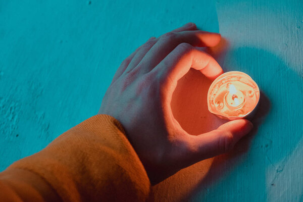 Чирок и апельсин отфильтрованы крупным планом женской руки, держащей маленькую свечку
