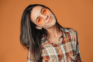 Yakın çekim sevimli gülümseyen genç esmer kız turuncu zemin üzerine