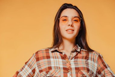 Yakın çekim sevimli gülümseyen genç esmer kız turuncu zemin üzerine