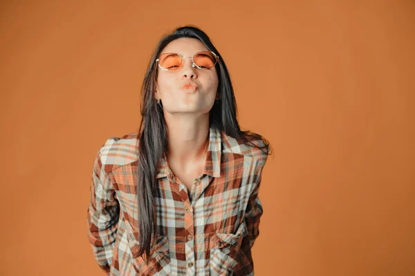 Bonito jovem morena menina no envio ar beijo para câmera no laranja — Fotografia de Stock