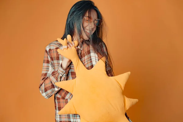 Joven chica morena caucásica con sol de juguete sobre fondo naranja Imagen de archivo
