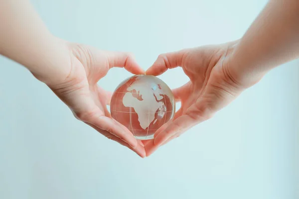 Hands in shape of heart  holding glass globe of Africa and Europ