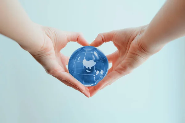 Ręce w kształcie serca, trzymając niebieskie szkło globe Polska — Zdjęcie stockowe