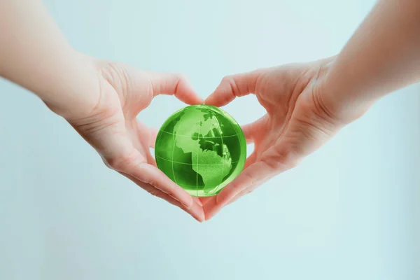 Mãos em forma de coração segurando globo de vidro verde do Sul e — Fotografia de Stock