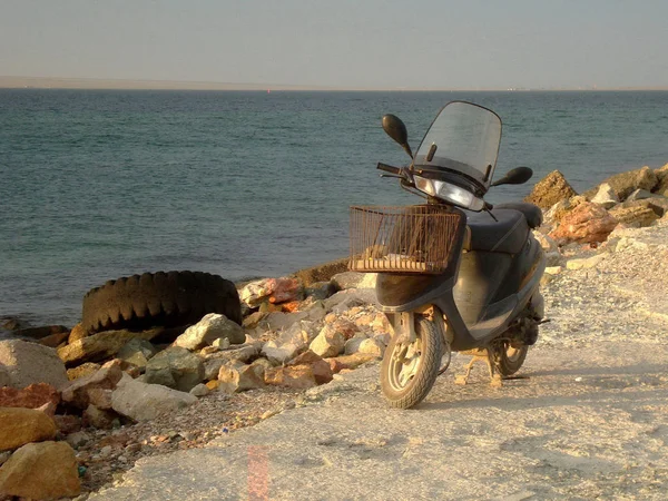 Oude motor scooter op de rotsachtige oever van de Broad Sea Bay in de — Stockfoto