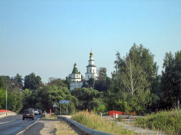 Highway past the monastery with a high temple on a Sunny day. — Stock Photo, Image