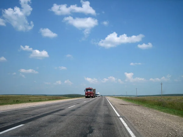 La carretera del coche en las grietas va lejos en la distancia en un br — Foto de Stock