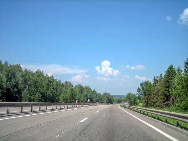Een gladde, vlakke snelweg loopt voorwaarts door het bos. Stockfoto