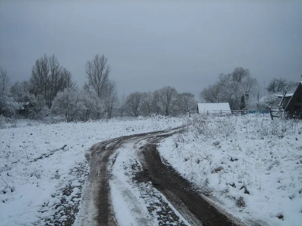 Bulutlu bir kış d üzerinde eski terk edilmiş bir köyde Çamurlu toprak yol — Stok fotoğraf